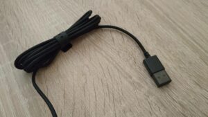 Detalle del cable enrollado con el conector USB macho con su capuchón plástico puesto.